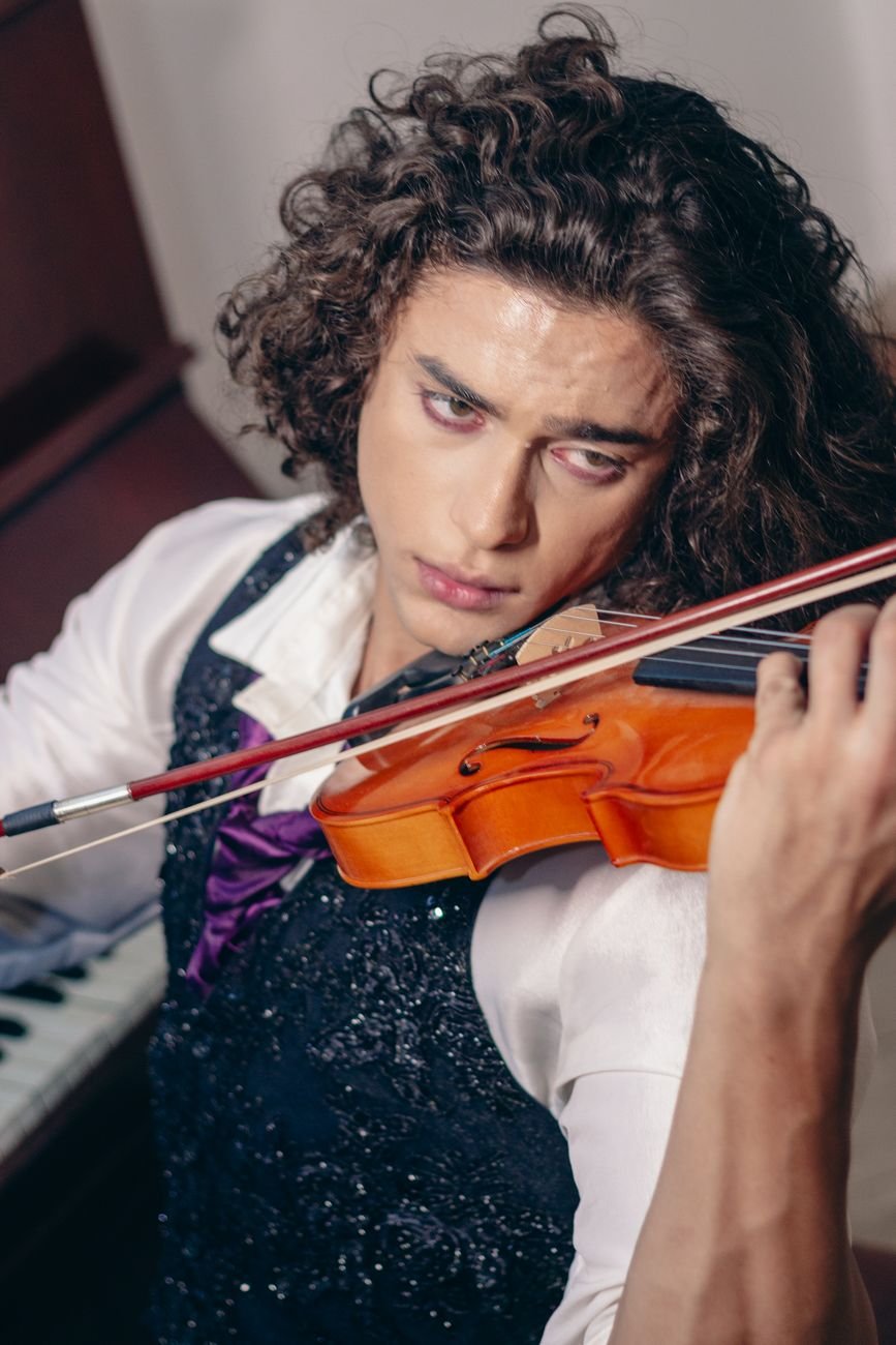 A focused young man passionately playing the violin indoors