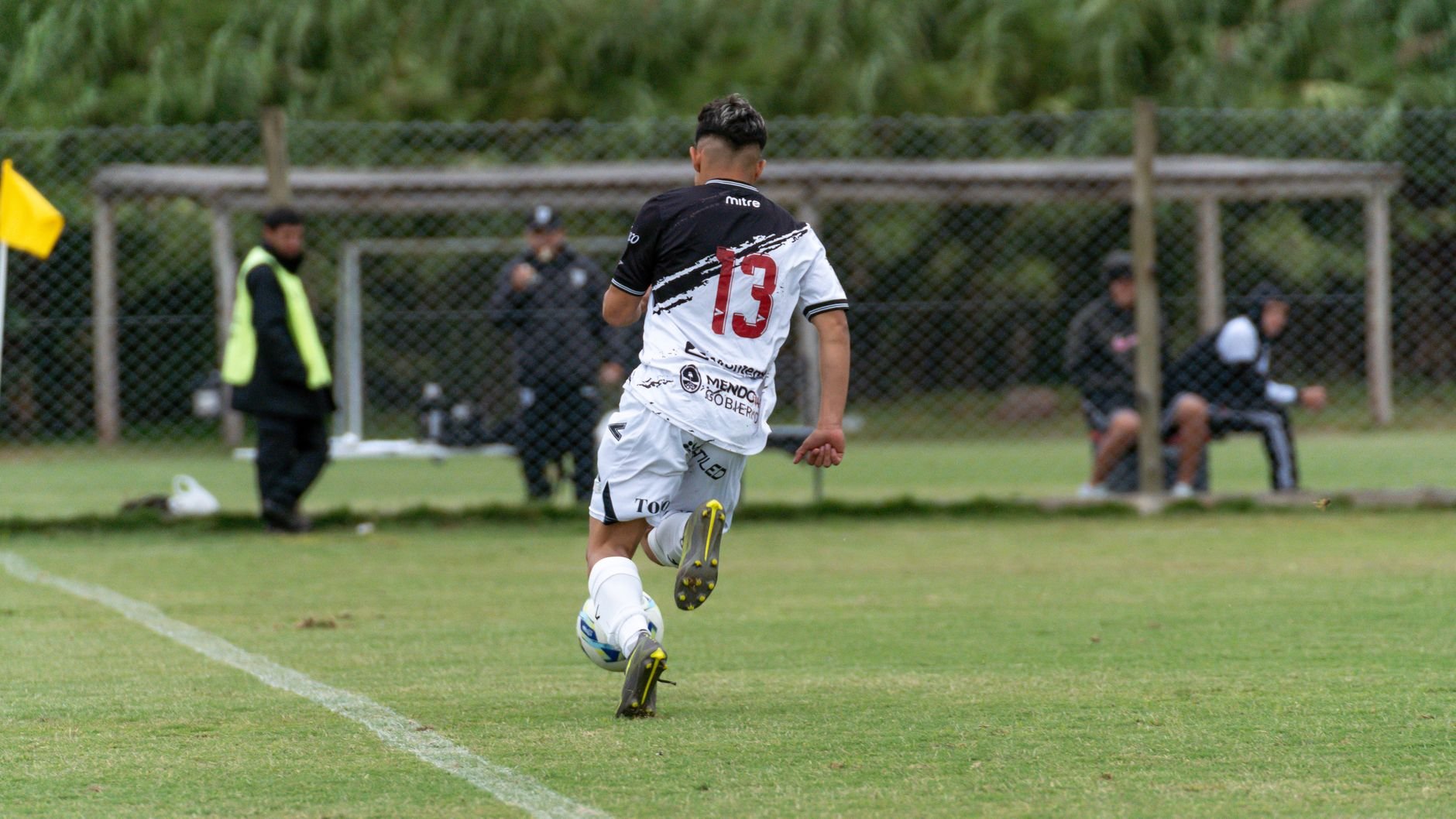 A teenager in soccer gear sprinting with the ball on a grassy field during a match